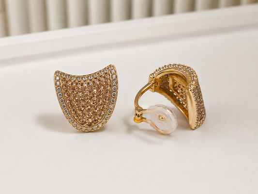 Gold plated crystal clip-on earring pair shown next to a pearl ring on a white surface