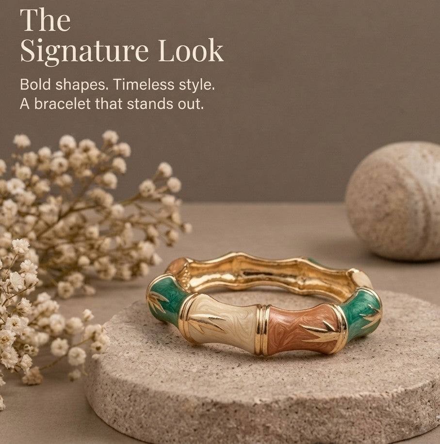 NAXAYA Bamboo Muse enamel bangle resting flat on beige stone, showing multicolour segments and a gold-tone interior.