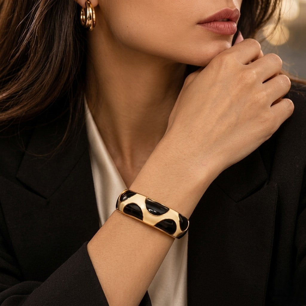 Model wearing NAXAYA Modern Noir gold-tone kada bracelet with black half-moon enamel details and a black blazer.