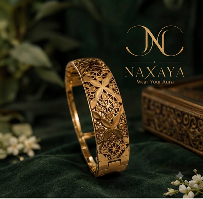 axaya broad gold filigree bangle on emerald green fabric with gold logo.