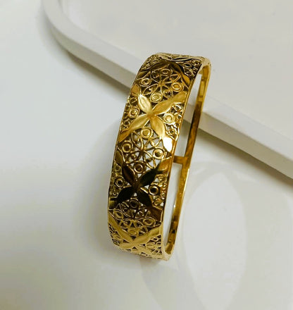  Close-up of Naxaya traditional gold filigree cuff bracelet worn on a wrist.